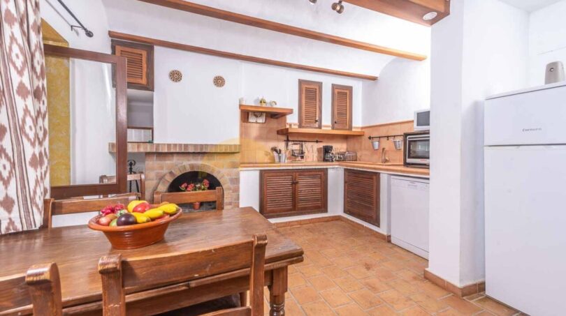 Rustikale Küche der Finca Son Macià mit Holzmöbeln, Kamin, Terrakottaboden und mediterranem Charme.