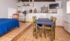 Helles Studio der Finca Son Macià mit Esstisch, Schlafbereich auf Podest und Holzbalkendecke.