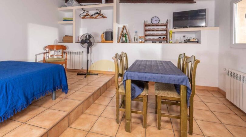 Helles Studio der Finca Son Macià mit Esstisch, Schlafbereich auf Podest und Holzbalkendecke.