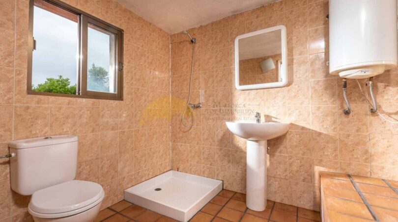 Badezimmer der Finca in Son Macià mit Dusche, WC, Waschbecken und Fliesenwänden in Sandtönen