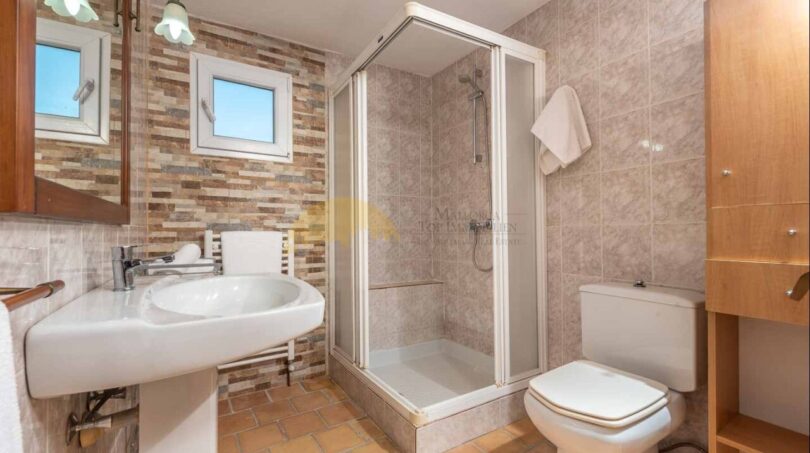Helles Badezimmer der Finca mit Duschkabine, WC, Waschtisch und Natursteinwand in Son Macià