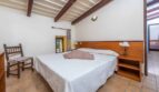 Schlafzimmer der Finca in Son Macià mit Doppelbett, Holzbalkendecke und Terrakottaboden
