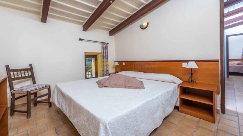 Schlafzimmer der Finca in Son Macià mit Doppelbett, Holzbalkendecke und Terrakottaboden