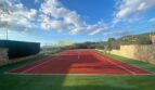 Roter Tennisplatz mit grünem Kunstrasen, Steinmauern und Panoramablick auf die Hügel von Son Macià