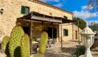 Rustikale Finca in Son Macià mit Natursteinmauern, überdachter Terrasse und Kaktus im Vordergrund.