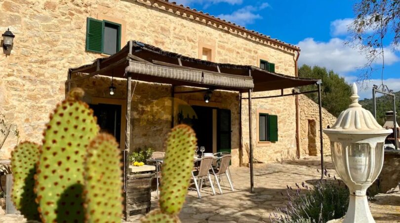 Rustikale Finca in Son Macià mit Natursteinmauern, überdachter Terrasse und Kaktus im Vordergrund.