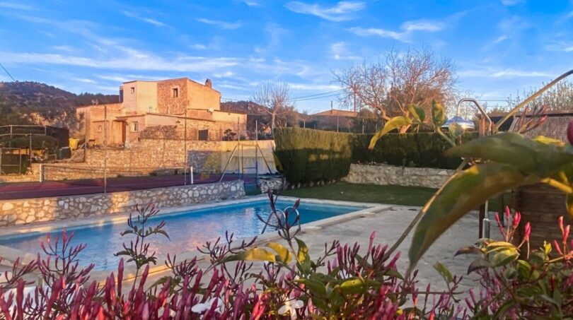 Außenbereich der Finca in Son Macià mit Pool, Steinterrasse, Garten und Blick auf das Rustikal-Steinhaus.