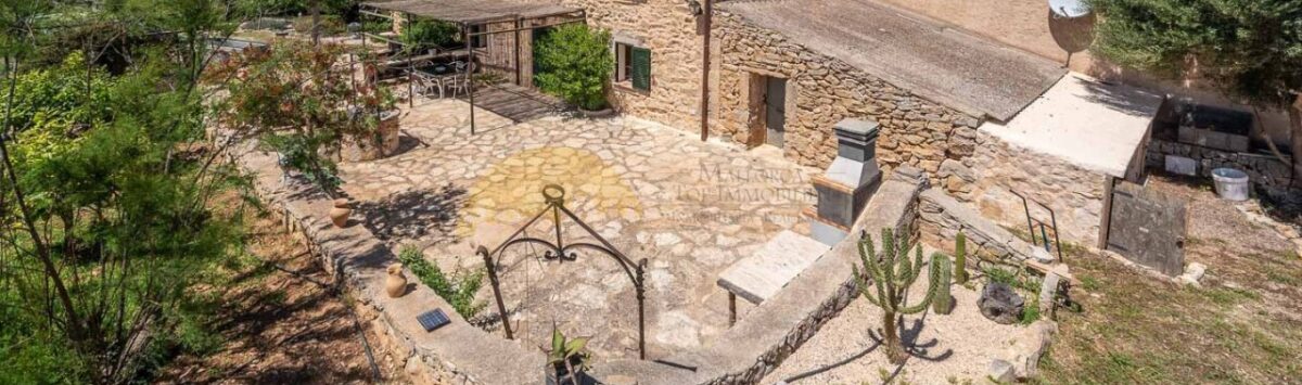 Luftaufnahme einer rustikalen Steinhaus-Finca in Son Macià mit Innenhof, Terrasse und weitläufigem Naturgrundstück.