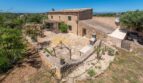 Luftaufnahme einer rustikalen Steinhaus-Finca in Son Macià mit Innenhof, Terrasse und weitläufigem Naturgrundstück.