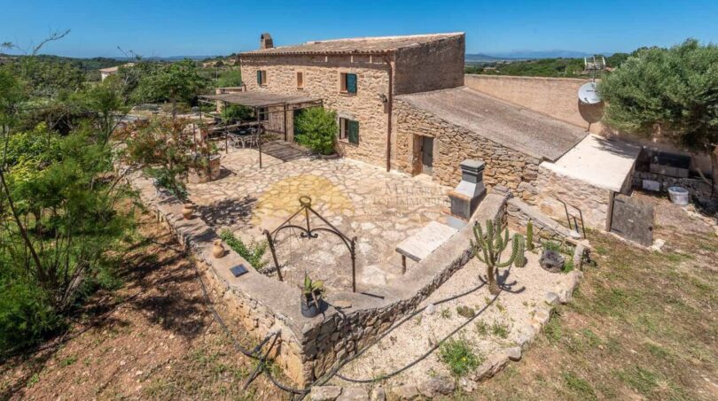 Luftaufnahme einer rustikalen Steinhaus-Finca in Son Macià mit Innenhof, Terrasse und weitläufigem Naturgrundstück.
