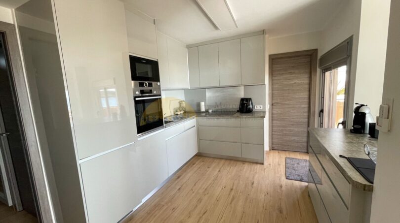 Moderne Einbauküche mit weißen Hochglanzfronten, Bosch-Geräten und hellem Parkettboden im Strandapartment Magaluf.