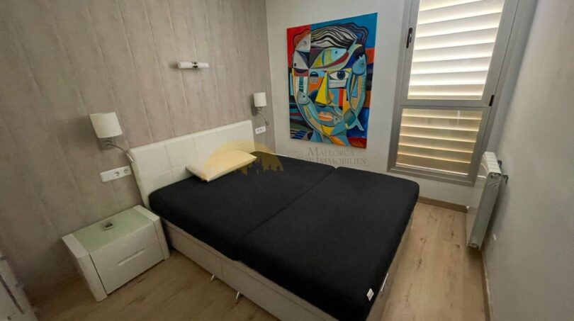Helles Schlafzimmer mit Doppelbett, Holzboden, modernem Kunstgemälde und Fensterläden im Strandapartment Magaluf.