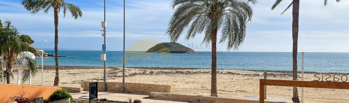 Terrasse des Strandapartments in Magaluf mit Meerblick, Palmen, Holzdeck und kleiner Insel im Hintergrund