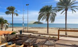 Terrasse des Strandapartments in Magaluf mit Meerblick, Palmen, Holzdeck und kleiner Insel im Hintergrund