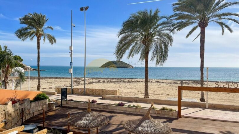 Terrasse des Strandapartments in Magaluf mit Meerblick, Palmen, Holzdeck und kleiner Insel im Hintergrund