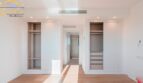 Helles Schlafzimmer mit eingebautem Kleiderschrank und Durchgang zum Bad im Neubau-Landhaus Porto Cristo