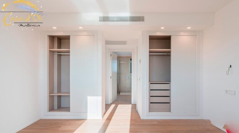 Helles Schlafzimmer mit eingebautem Kleiderschrank und Durchgang zum Bad im Neubau-Landhaus Porto Cristo