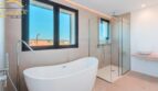 Modernes Badezimmer mit freistehender Badewanne, Glasdusche und Bergblick im Neubau-Landhaus Porto Cristo