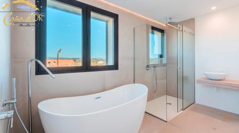Modernes Badezimmer mit freistehender Badewanne, Glasdusche und Bergblick im Neubau-Landhaus Porto Cristo