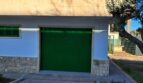 Außenansicht Anwesen Alcúdia: weiße Fassade mit grünen Fensterläden, Garage und Balkon, Olivenbaum im Garten