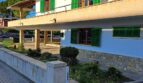 Zweistöckiges Ferienhaus in Alcúdia mit grünen Fensterläden, Balkon, Natursteinverkleidung und gepflegtem Außenbereich.