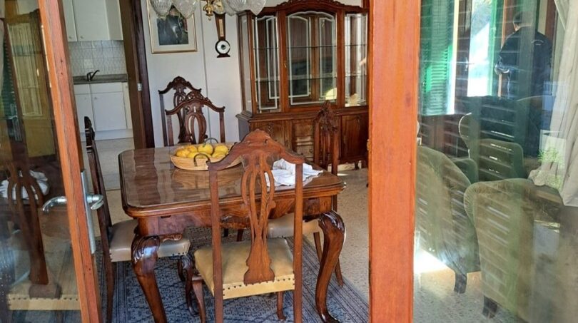 Elegantes Esszimmer mit antikem Holzmobiliar, Kronleuchter und Vitrinenschrank in Alcúdia-Anwesen.