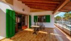 Terraza cubierta con persianas verdes, techo de madera y mesa de bistró, cerca de la playa en Alcudia