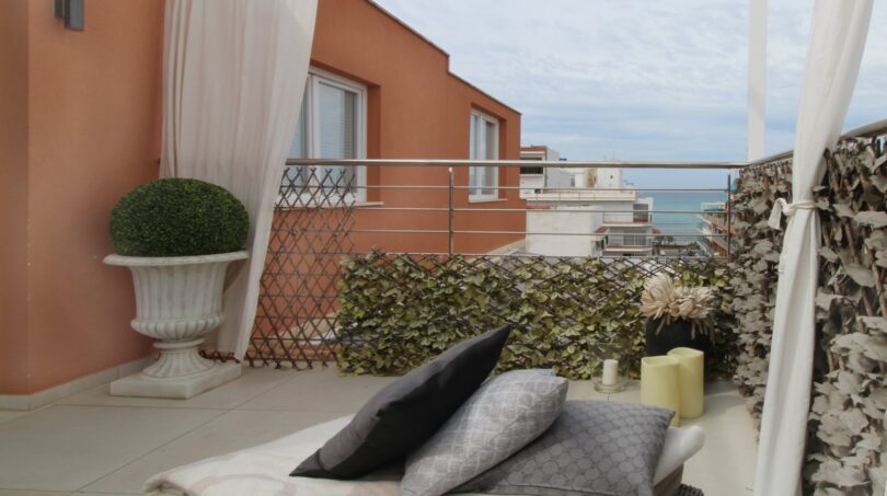 Penthouse-Terrasse mit Lounge-Bett, Kissen, Meerblick und elegantem Pflanzenschmuck in Strandnähe Palma