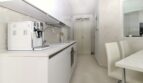 Moderne weiße Küche mit Kaffeemaschine, Einbaugeräten und angrenzendem Essbereich im Penthouse Palma de Mallorca