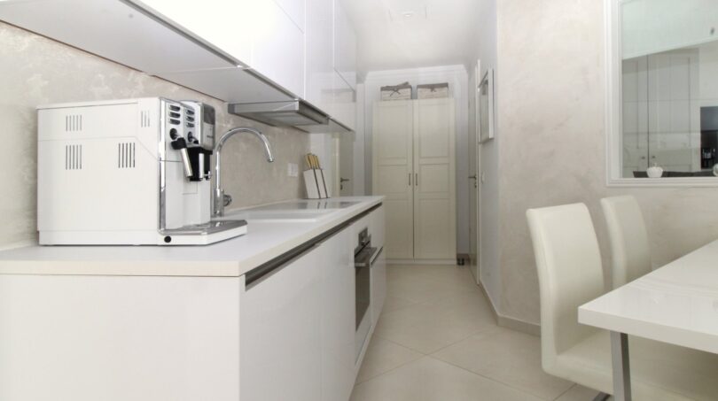 Moderne weiße Küche mit Kaffeemaschine, Einbaugeräten und angrenzendem Essbereich im Penthouse Palma de Mallorca