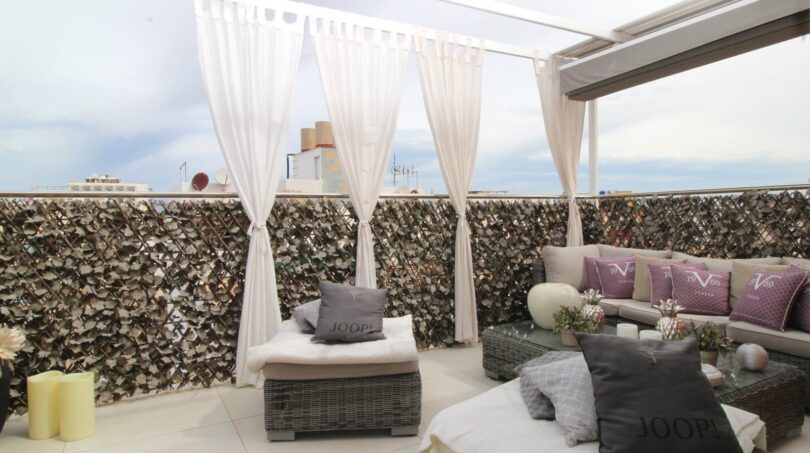 Elegante Dachterrasse des Penthouses mit Loungemöbeln, weißen Vorhängen und Meerblick in Palma de Mallorca