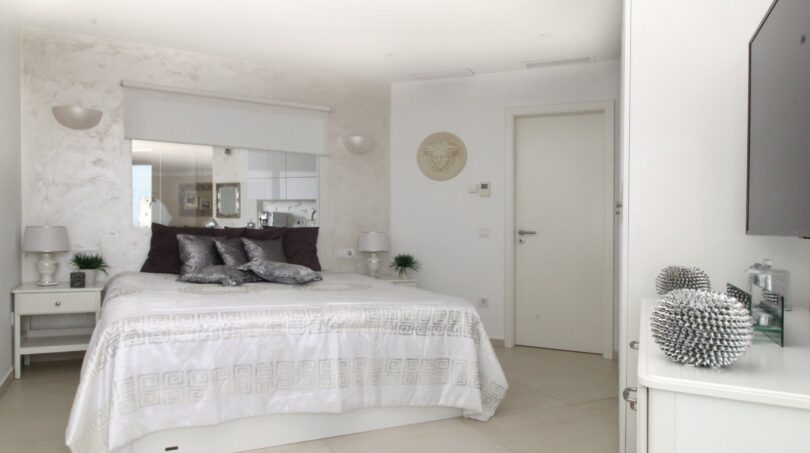 Elegantes Schlafzimmer im Penthouse Palma de Mallorca mit Doppelbett, Marmor-Akzentwand und hochwertiger Ausstattung.