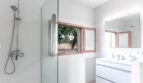 Moderno baño de la finca Porto Cristo con ducha de cristal, doble lavabo y ventanas con vistas a la naturaleza