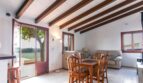 Luminosa sala de estar de la finca con techo de vigas de madera, mesa de comedor y vista al jardín verde.