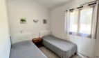 Dormitorio de la finca Porto Cristo con dos camas individuales, aire acondicionado y ventanas con vista al jardín