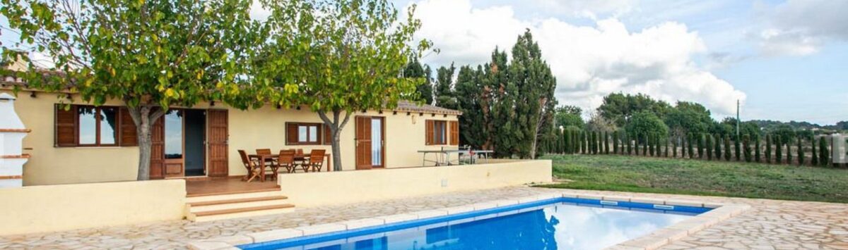 Finca Porto Cristo: Área exterior con piscina azul, suelo de piedra natural y terraza cubierta con conjunto de asientos