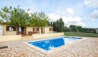 Finca Porto Cristo: Área exterior con piscina azul, suelo de piedra natural y terraza cubierta con conjunto de asientos