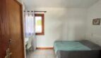 Luminoso dormitorio de la finca en Porto Cristo con cama doble, escritorio y ventanas con vista al jardín.