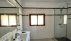 Luminoso baño de la finca en Porto Cristo con ducha de cristal, azulejos blancos y cenefa decorativa