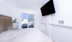 Helles Schlafzimmer im Luxus-Penthouse Palma mit Doppelbett, Wandtv und Balkonzugang mit Stadtblick.