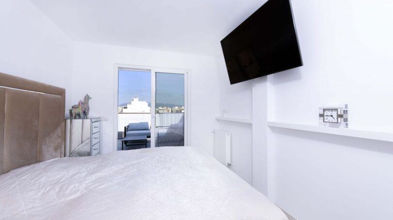 Helles Schlafzimmer im Luxus-Penthouse Palma mit Doppelbett, Wandtv und Balkonzugang mit Stadtblick.