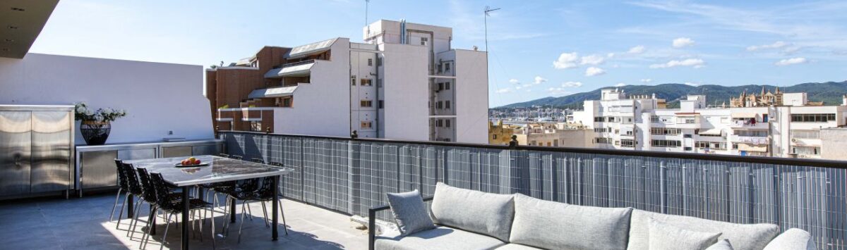 Sonnige Dachterrasse des Luxus-Penthouses in Palma mit Lounge, Esstisch und Stadtpanorama-Blick.