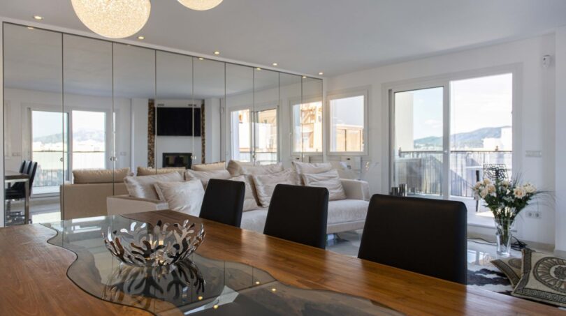 Offener Wohn- und Essbereich des Luxus-Penthouses in Palma mit elegantem Holztisch und heller Sofaecke