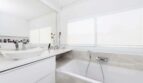 Modernes weißes Badezimmer mit Einbaubadewanne, Waschtisch und großem Spiegel im Luxus-Penthouse Palma