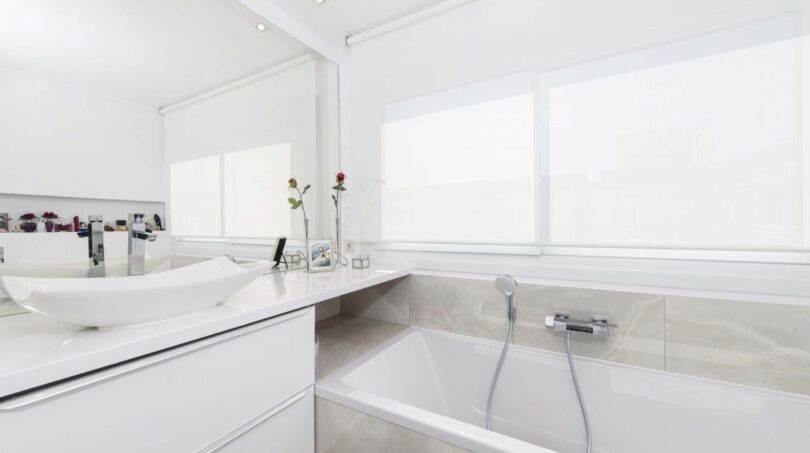 Modernes weißes Badezimmer mit Einbaubadewanne, Waschtisch und großem Spiegel im Luxus-Penthouse Palma