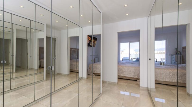 Ankleidebereich mit raumhohen Spiegelschränken im Luxus-Penthouse Palma, helle Bodenfliesen, Blick ins Schlafzimmer