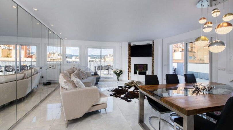 Helles Wohnzimmer mit Spiegelwand, Designermöbeln, Kamin und Panoramafenstern im Luxus-Penthouse Palma