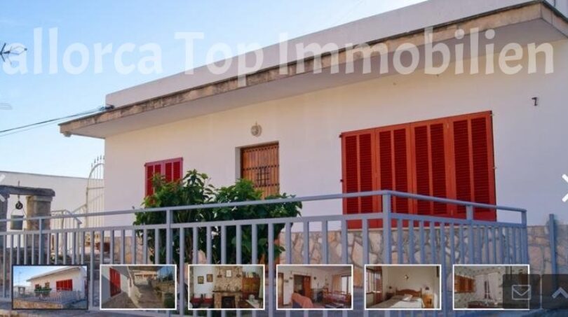 Außenansicht Zweifamilienhaus Portocolom: weißes Gebäude mit roten Fensterläden, Balkon und Metallgeländer.