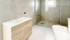 Modernes Badezimmer mit Walk-in-Dusche, Holzwaschtisch und WC im Zweifamilienhaus Portocolom