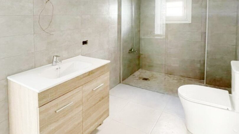 Modernes Badezimmer mit Walk-in-Dusche, Holzwaschtisch und WC im Zweifamilienhaus Portocolom